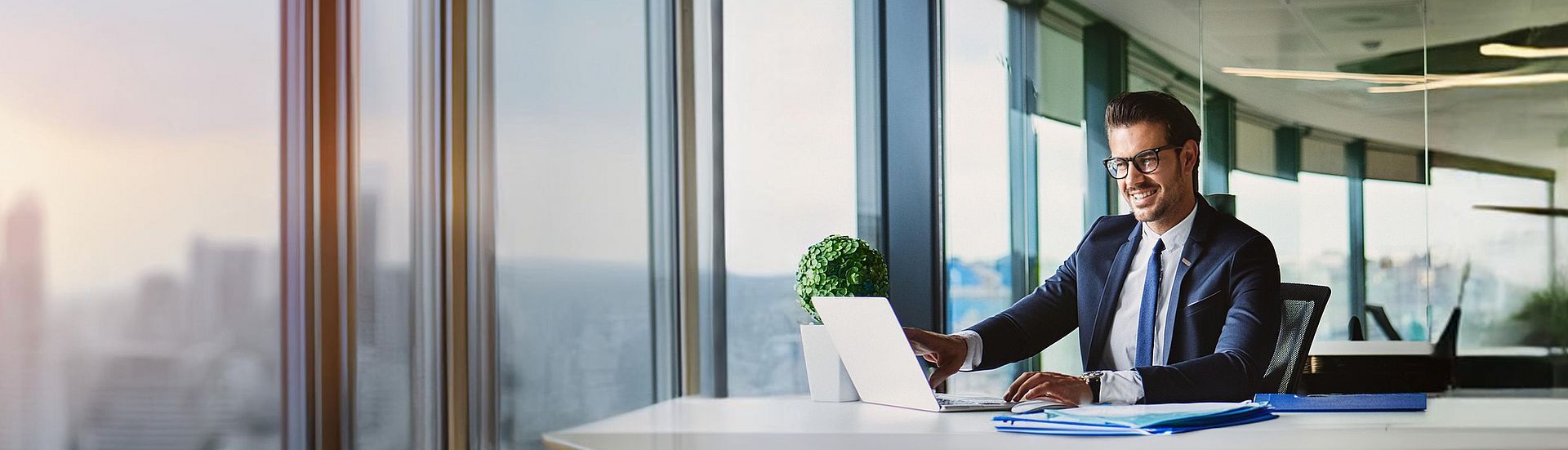 Mann sitzt am Schreibtisch vor Laptop