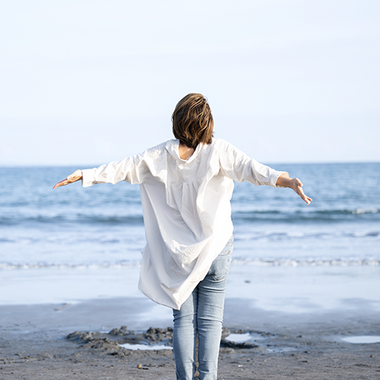 Eine Frau steht am Strand und blickt ins Meer.