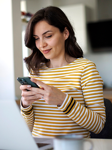 Eine Frau schaut zufrieden auf ihr Smartphone.