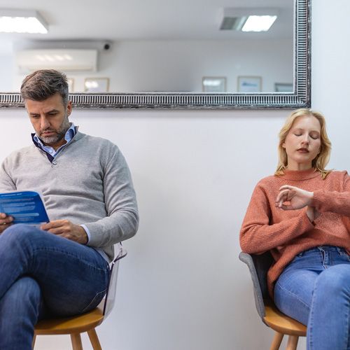 Ein Mann und eine Frau sitzen in einem Wartezimmer.