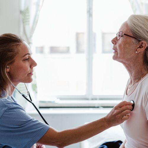 Eine Ärztin hört den Brustkorb einer Patientin ab.