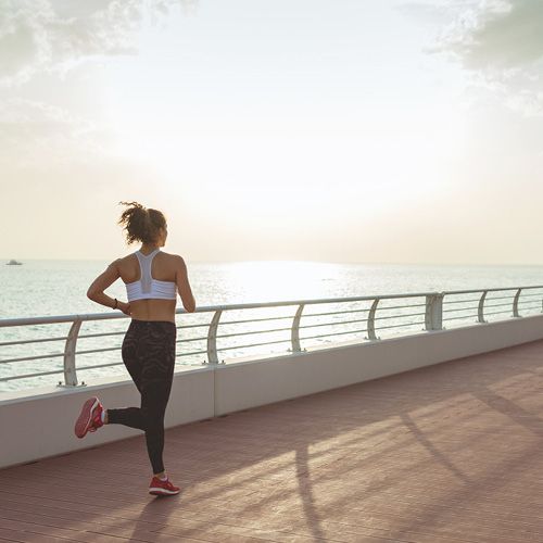 Eine Frau joggt am Meer entlang.