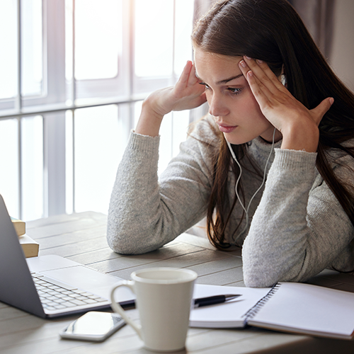 Eine Schülerin sitzt zuhause angestrengt vor ihrem Laptop.