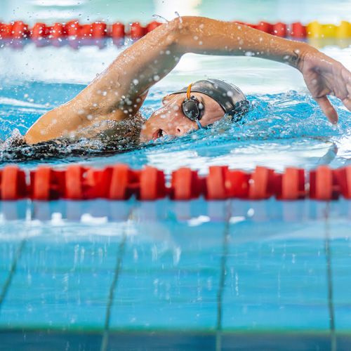 Eine Schwimmerin krault in einem Hallenbad.